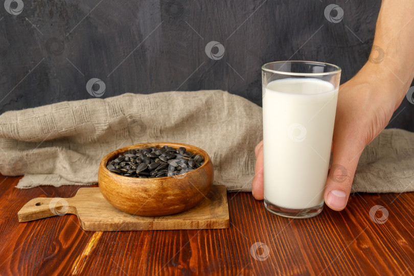 Скачать Молоко из семян подсолнечника, семечки на разделочной доске, деревянный фон фотосток Ozero