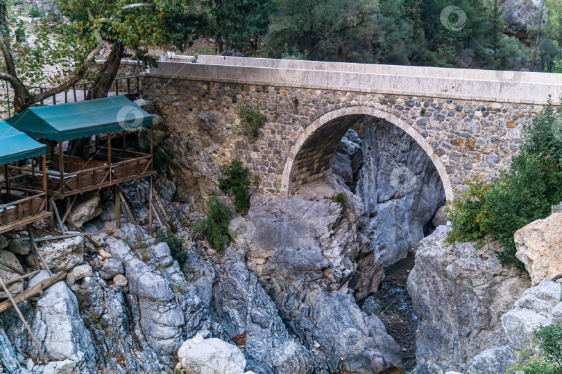 Скачать беседка-закусочная для туристов рядом с древнеримским мостом через тенистое ущелье в каньоне Кесме Богази, Турция фотосток Ozero