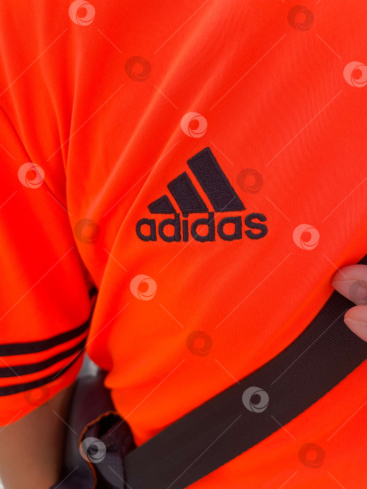 Скачать Тюмень, Россия - 30 августа 2022 года: логотип Adidas на мужской футболке. Adidas - немецкий дизайнер и производитель спортивной одежды и аксессуаров. Вертикальная фотография фотосток Ozero