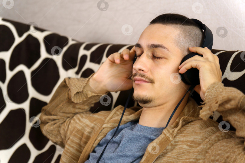 Скачать Мужчина слушает музыку. наушники наслаждайтесь прослушиванием современной музыки аудиокниги с закрытыми глазами медитируйте расслабляйтесь не испытывайте стресса расслабляйтесь дома фотосток Ozero