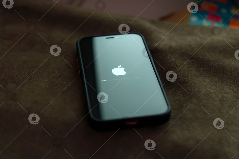 Скачать Тюмень, Россия - 01 октября 2022 года: Обновляется логотип Apple на смартфоне iPhone 12 mini. Избирательный фокус фотосток Ozero