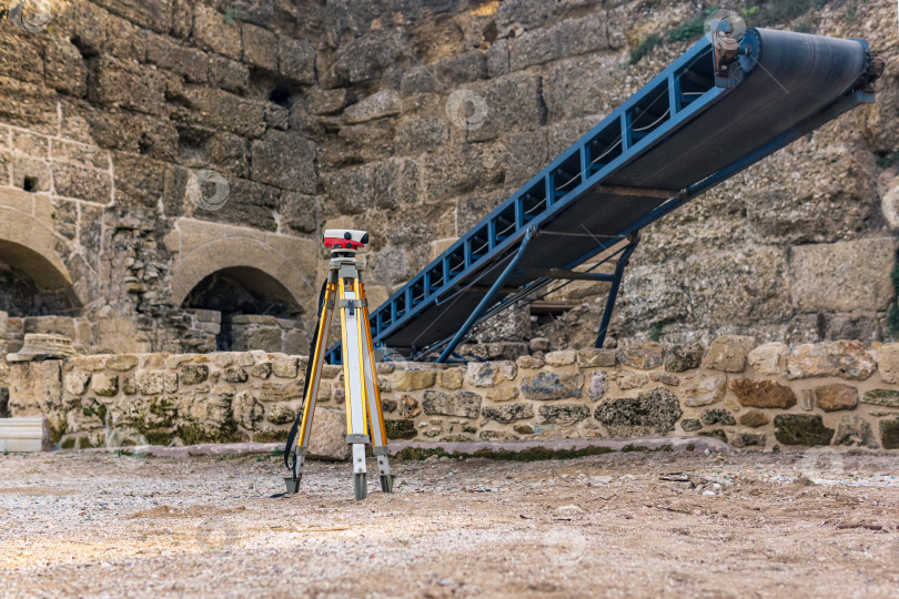 Скачать археологический объект среди древних руин с конвейером для грунта и теодолитом на переднем плане фотосток Ozero
