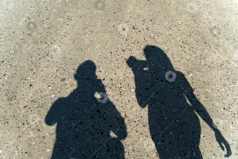 Скачать Тень двух людей на асфальте - это мужчина и женщина. Асфальт рядом с дорогой в солнечный день фотосток Ozero