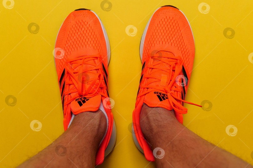 Скачать Тюмень, Россия - 13 ноября 2021 года: Новые кроссовки adidas оранжевого цвета. Логотип крупным планом. Избирательный фокус фотосток Ozero