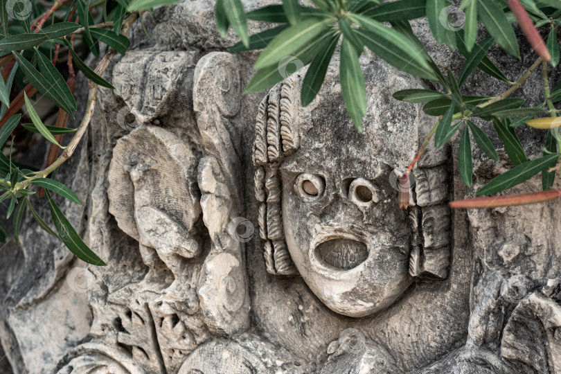 Скачать старинная каменная маска среди растительности в руинах древнего города Мира, Турция фотосток Ozero