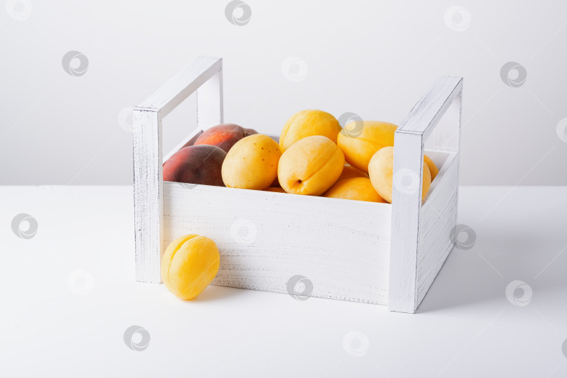 Скачать Деревянная коробка с абрикосами и персиками, выделенными на белом фоне фотосток Ozero