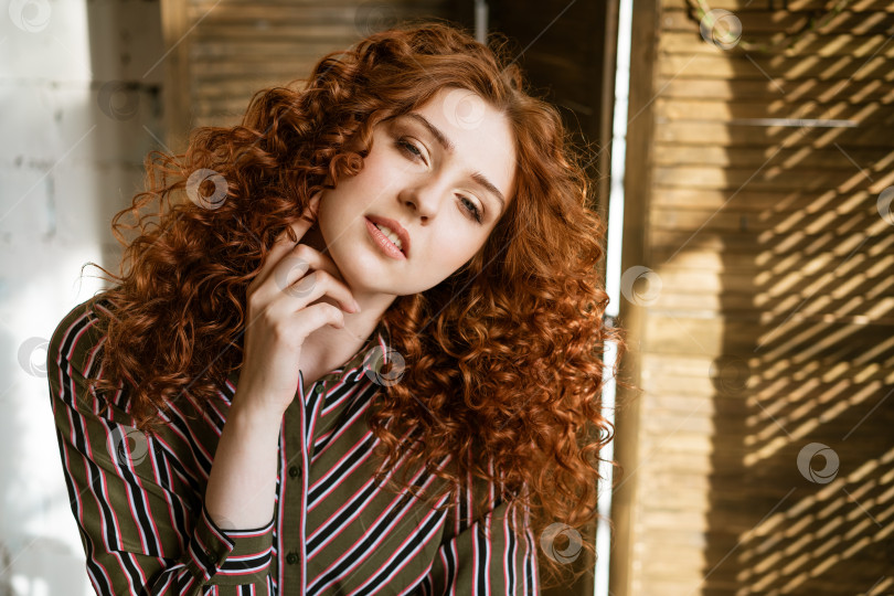 Скачать Портрет счастливой рыжеволосой молодой женщины у окна фотосток Ozero