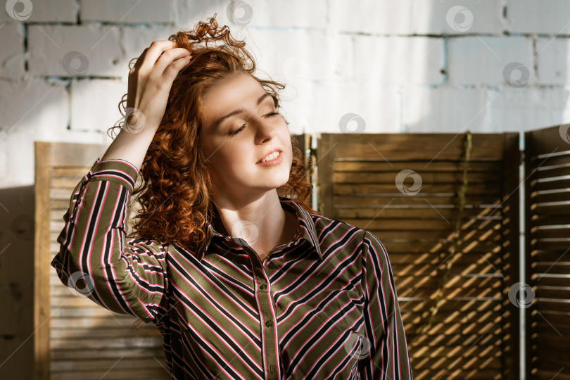 Скачать Портрет счастливой рыжеволосой молодой женщины у окна фотосток Ozero