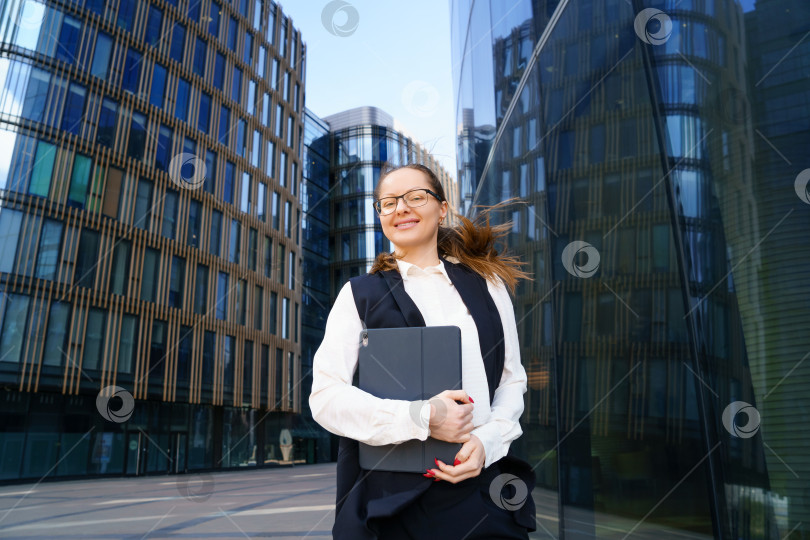 Скачать Деловая женщина стоит с ноутбуком возле офисного здания фотосток Ozero