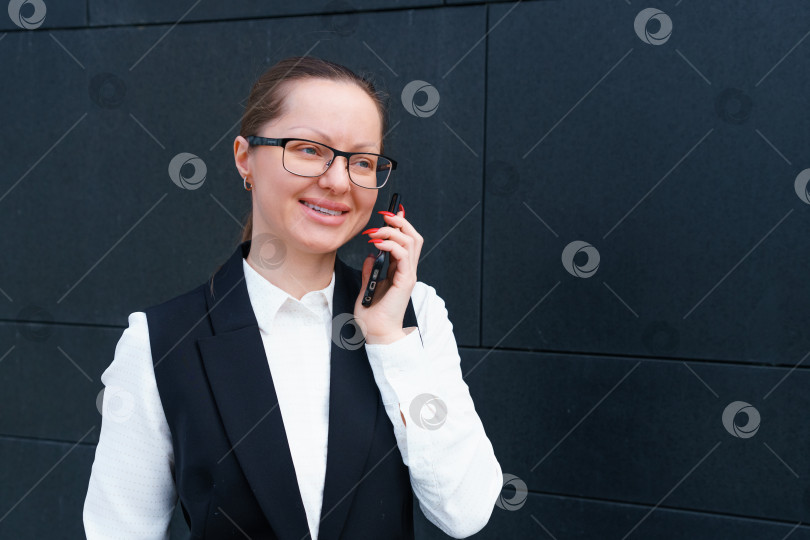 Скачать Успешная бизнесвумен разговаривает по мобильному телефону во время прогулки на свежем воздухе рядом фотосток Ozero