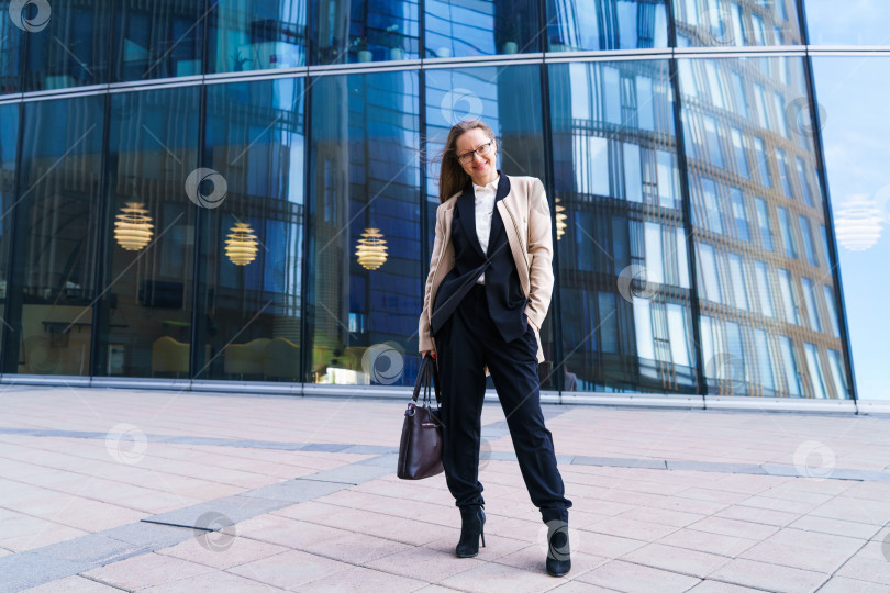 Скачать Успешная женщина в очках стоит перед офисным зданием с сумкой фотосток Ozero