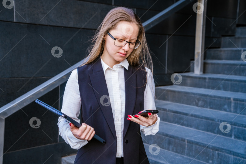 Скачать Успешная женщина разговаривает по мобильному телефону, держа ноутбук на заднем плане лестницы фотосток Ozero