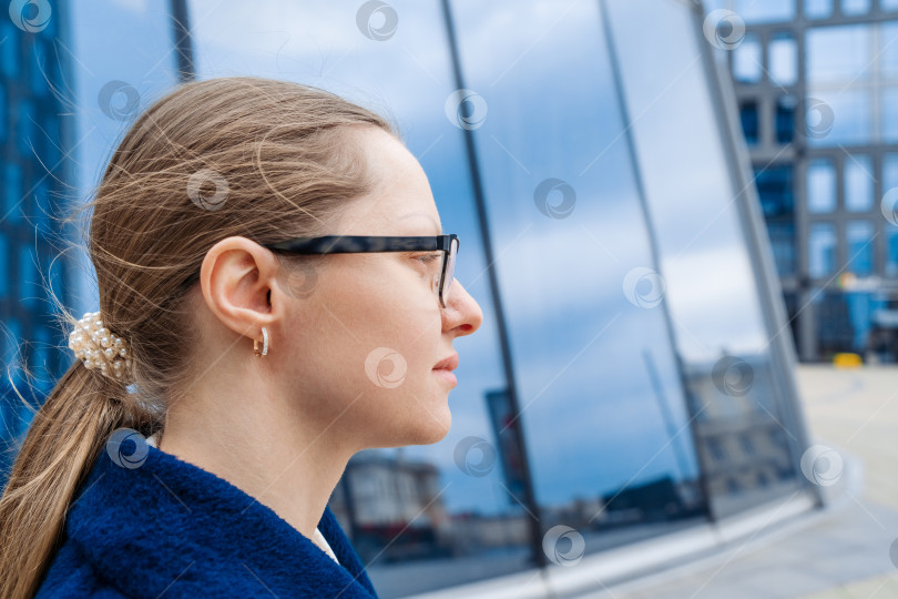 Скачать Портрет счастливой женщины в очках крупным планом, задумчиво смотрящей в сторону, в голубых тонах фотосток Ozero