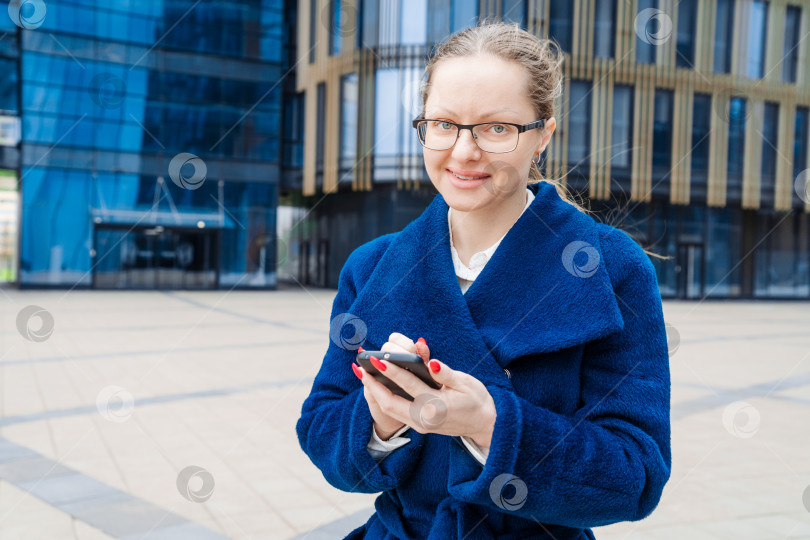 Скачать Успешная деловая женщина, делающая заметки и разговаривающая по мобильному телефону, в то время как фотосток Ozero