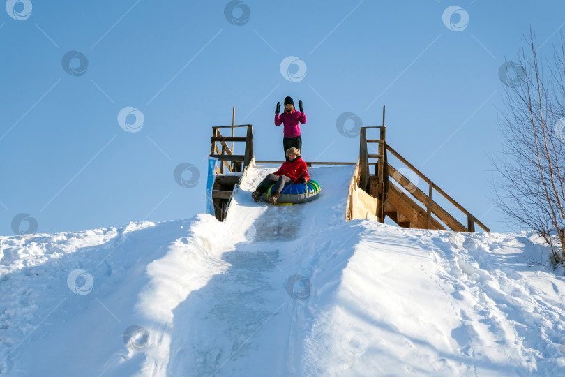 Скачать Веселая молодая женщина с зимним занятием на сноутюбинге, катается со снежной горки. Избирательный фокус фотосток Ozero
