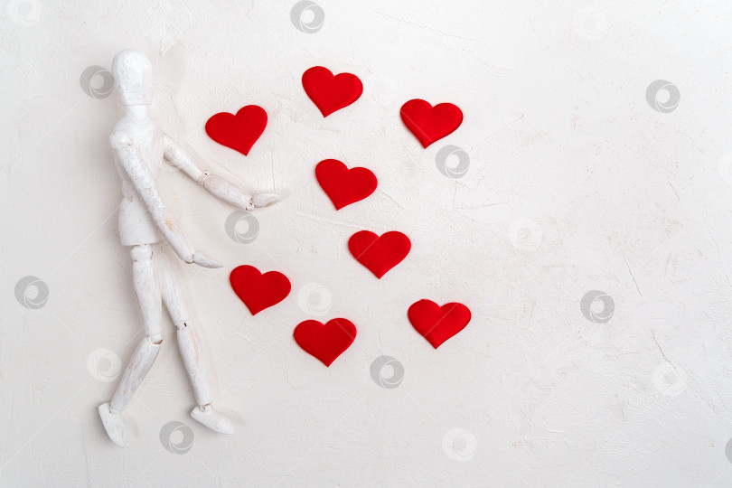 Скачать Деревянная фигурка манекена на белом фоне, украшенная красным сердцем, символизирует любовь и День Святого Валентина. Плоская поверхность фотосток Ozero