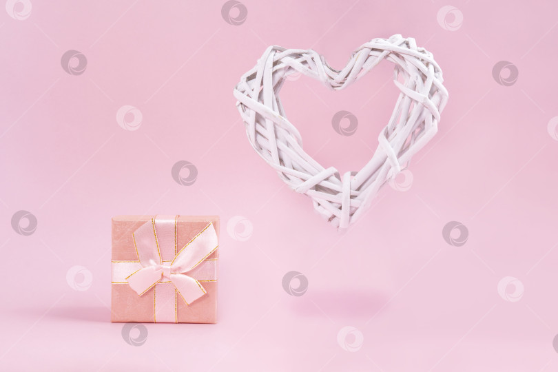 Скачать Белое сердечко и подарочная коробка на пастельно-розовом фоне. Концепция дня Святого Валентина. Плоская поверхность фотосток Ozero