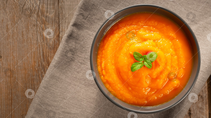 Скачать Вкусный тыквенно-морковный суп в миске на старом деревянном столе фотосток Ozero