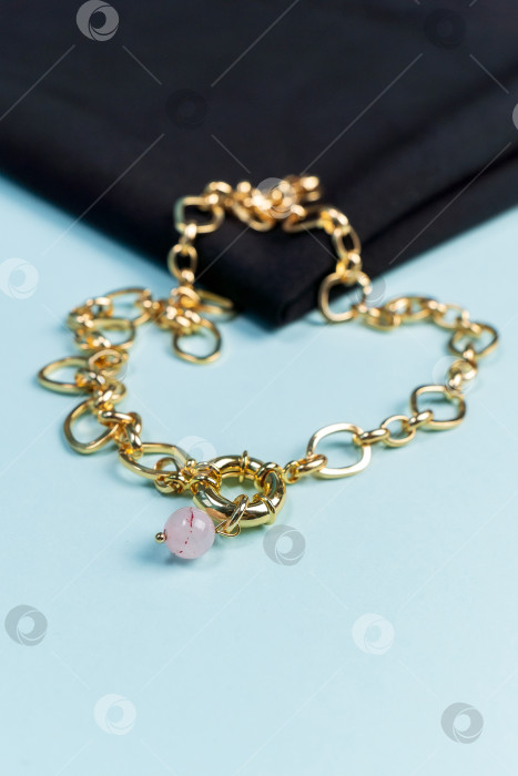 Скачать Ожерелье из натурального смешанного розового кварца на золотой цепочке. На синем фоне, вид сверху фотосток Ozero