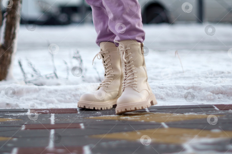 Скачать Крупный план белых женских сапог на снегу зимним днем, походка женщины. Избирательный фокус фотосток Ozero