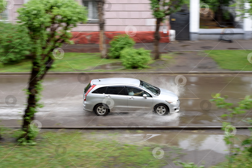 Скачать Серебристая машина едет по залитой дождем улице фотосток Ozero