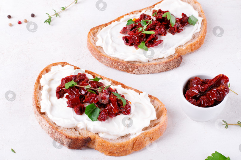 Скачать Брускетта с вялеными помидорами и сливочным сыром на ломтике хлеба чиабатта на белом столе фотосток Ozero
