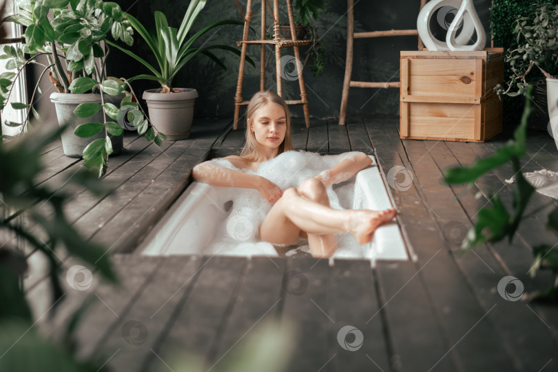 Скачать Натуральная красивая молодая блондинка принимает ванну с пузырьками в интерьере ванной комнаты с большим количеством зеленых планов фотосток Ozero