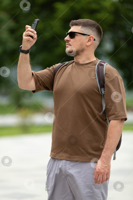 Скачать Турист-мужчина в солнцезащитных очках фотографирует достопримечательности на свой фотосток Ozero