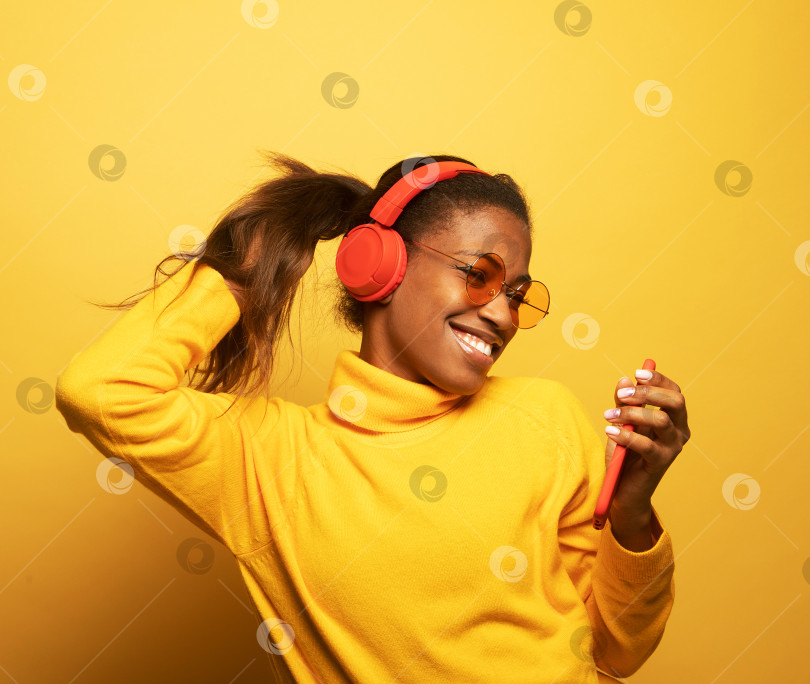 Скачать Концепция людей, музыки, эмоций. Молодая афроамериканка танцует в ритме мелодии. фотосток Ozero