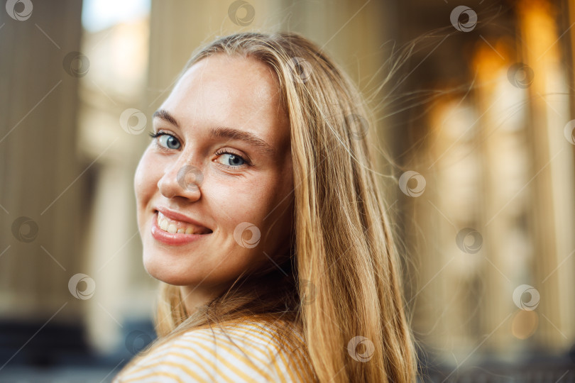Скачать Крупным планом веселая белокурая молодая женщина на улице, смотрящая в камеру с зубастой улыбкой. фотосток Ozero