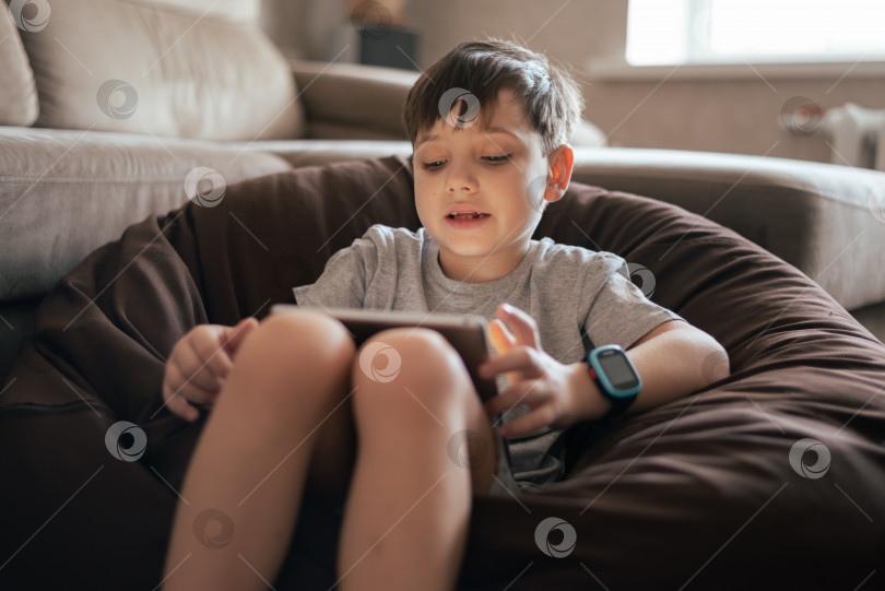 Скачать Маленький мальчик, использующий планшетную технологию и носящий умные часы. Современные технологии и концепция для детей фотосток Ozero