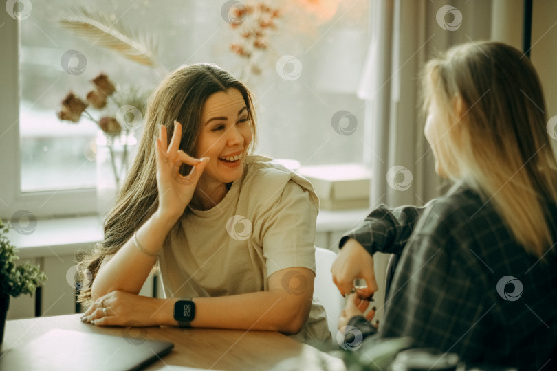 Скачать Дружелюбные коллеги-женщины, имеющие хорошие отношения, приятная беседа на рабочем месте во время кофе-брейка фотосток Ozero