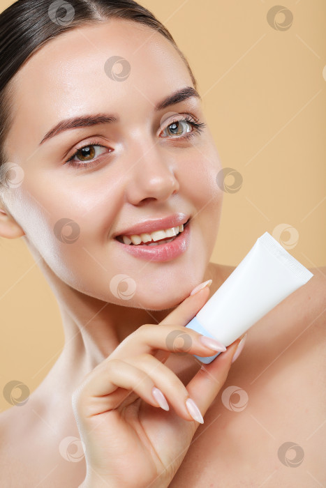 Скачать Красивый портрет улыбающейся красивой молодой женщины, держащей в руках тюбик с кремом для лица фотосток Ozero