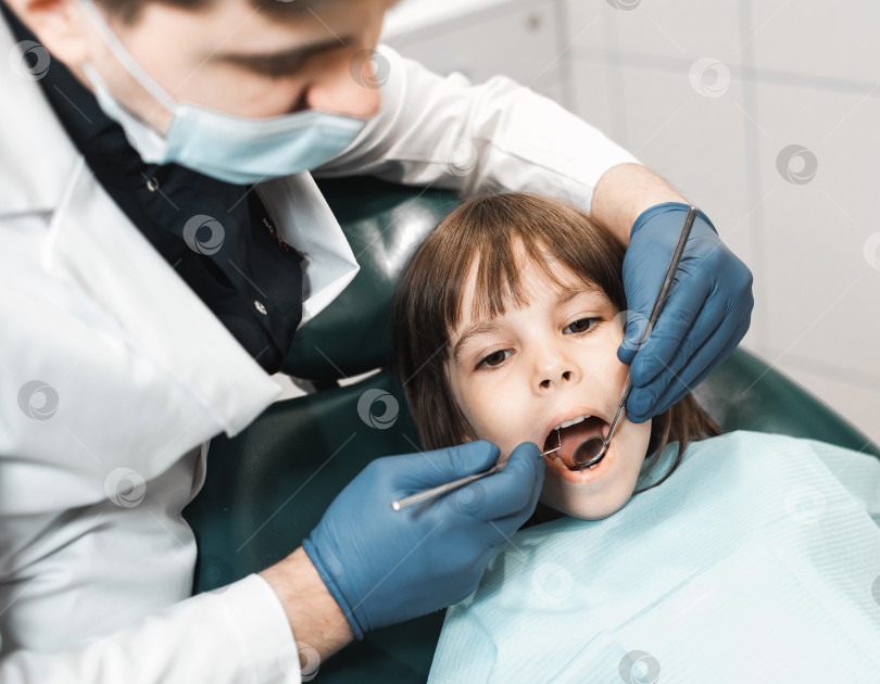 Скачать Люди, медицина, стоматология, технологии и концепция здравоохранения. Мужчина-стоматолог работает с маленькой девочкой в клинике. фотосток Ozero