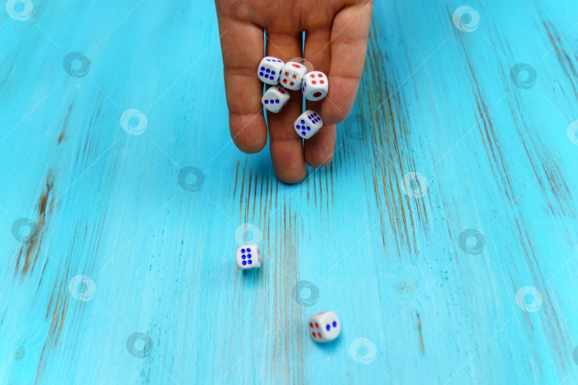 Скачать Рука бросает кости на синее деревянное игровое поле. Удача и азарт. Концепция стратегии настольных игр фотосток Ozero