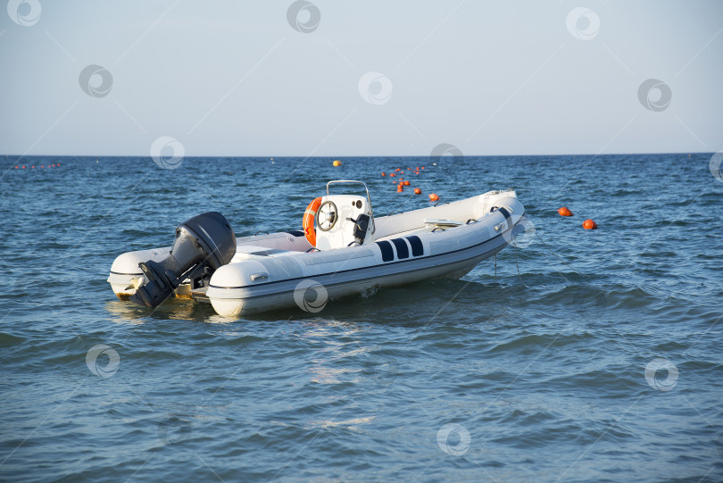 Скачать Надувная лодка с мотором в море на закате. фотосток Ozero