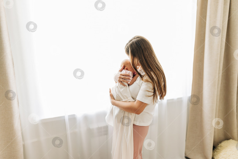 Скачать Мама со своим малышом новорожденный младенец малыш ребенок дома ухаживает в спальне, надевает одежду. Женщина семья женское здоровье и материнство фотосток Ozero