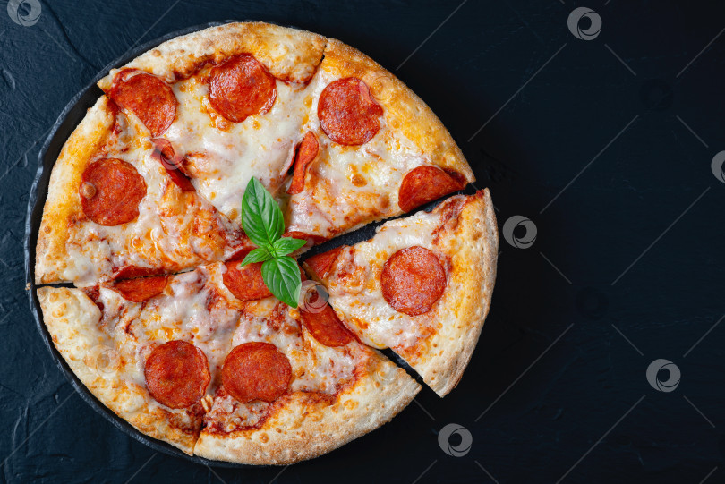 Скачать Горячая пицца с пепперони и базиликом на черном бетонном фоне. Верхний фотосток Ozero
