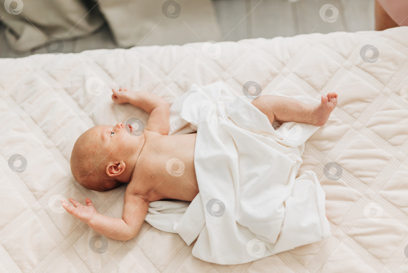 Скачать Маленький ребенок малыш новорожденный, лежащий в помещении дома в постели фотосток Ozero