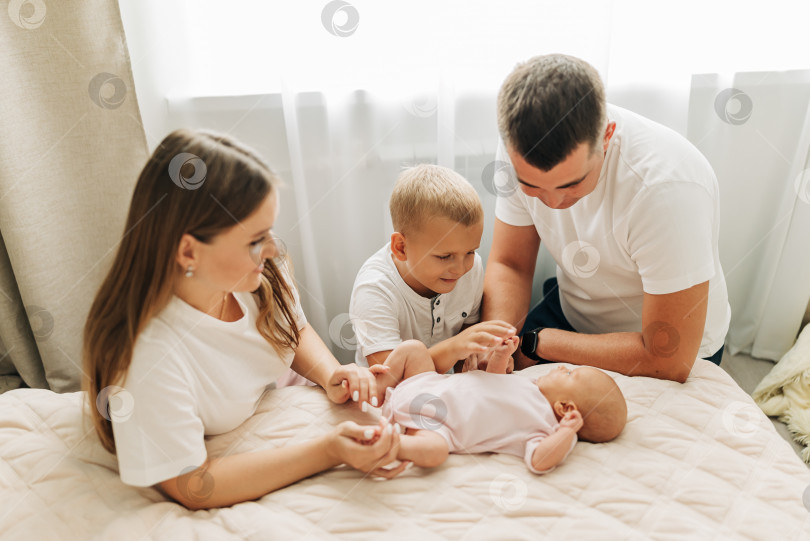 Скачать Семейный портрет родителей с новорожденным ребенком и старшим сыном. Счастье и любовь дома в закрытом помещении фотосток Ozero