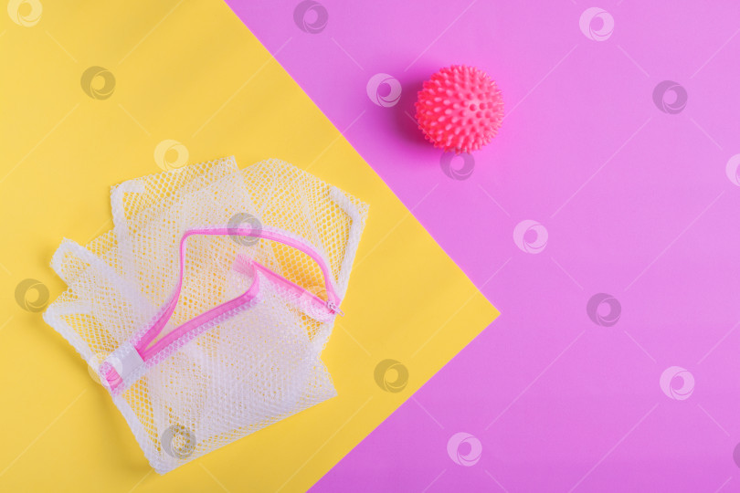 Скачать Мешок для белья и мяч для стиральной машины на геометрическом розово-желтом фоне. фотосток Ozero
