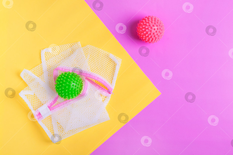 Скачать Мешок для белья и мяч для стиральной машины на геометрическом розово-желтом фоне. фотосток Ozero