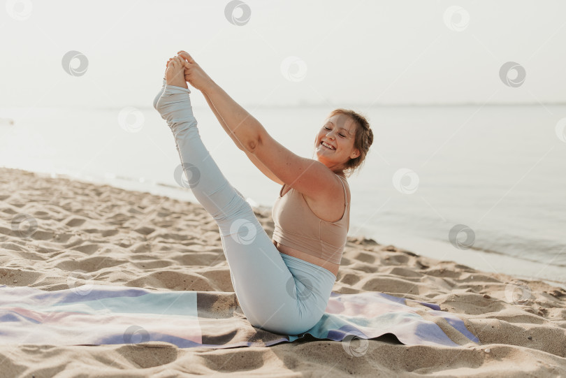 Скачать Белая женщина, практикующая йогу на песчаном пляже на берегу моря на восходе солнца. Женское здоровье и хорошее самочувствие. Позитивное спортивное тело. Настоящие позы инструктора фотосток Ozero
