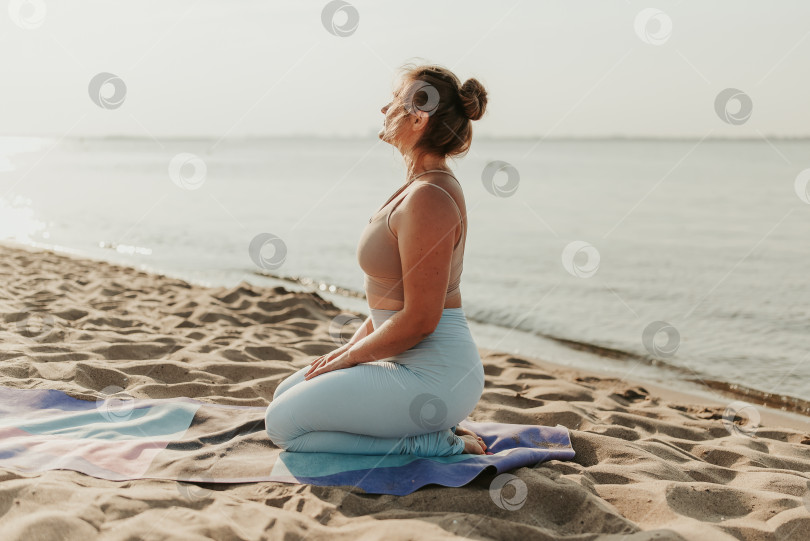 Скачать Белая женщина, практикующая йогу на песчаном пляже на берегу моря на восходе солнца. Женское здоровье и хорошее самочувствие. Позитивное спортивное тело. Настоящие позы инструктора фотосток Ozero