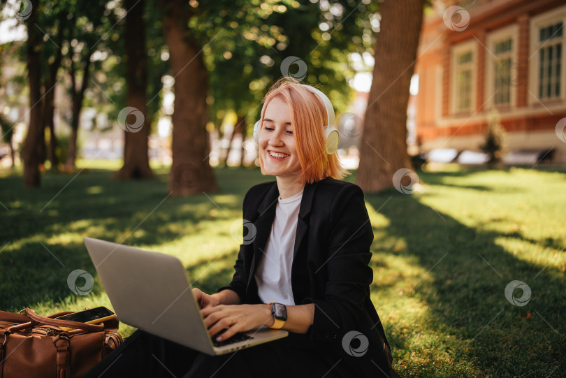 Скачать Симпатичная молодая кавказская женщина выходит на прогулку в парк с кофе и ноутбуком. Работа на открытом воздухе фотосток Ozero