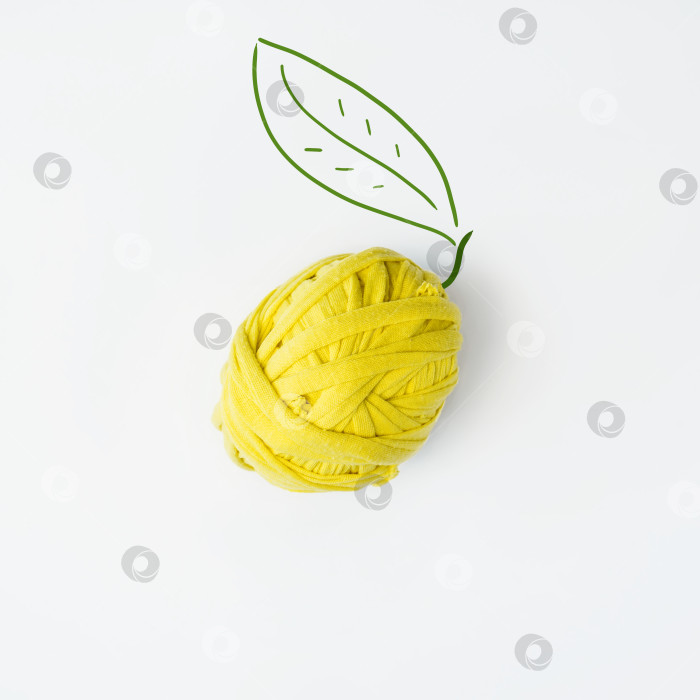Скачать Лимон, сделанный из шарика желтой ткани. Креативная концепция. Вязаный фрукт на белом фоне, ровный слой. фотосток Ozero