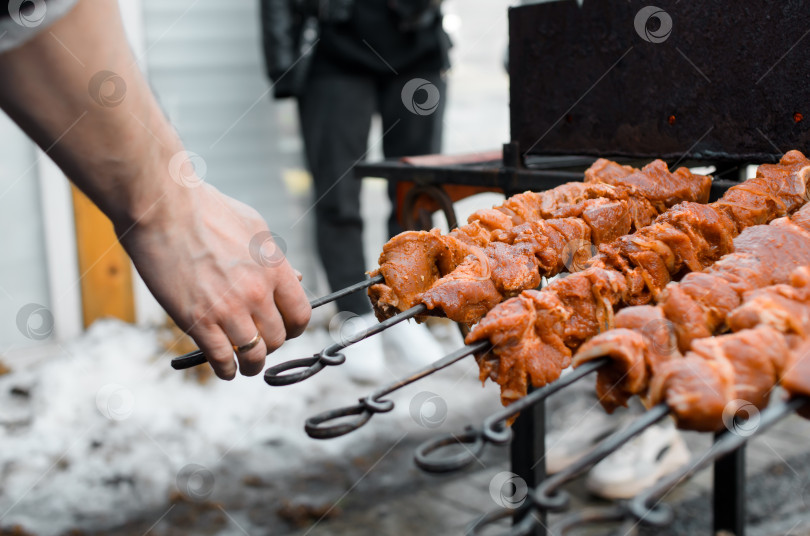 Скачать Готовим мясо на углях снаружи. Мужская рука, держащая шашлык крупным планом, выборочный фокус. фотосток Ozero