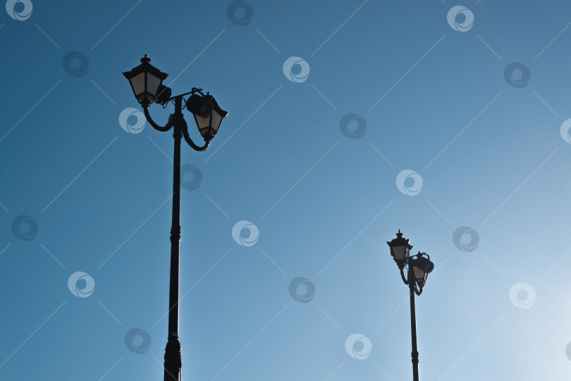 Скачать Два старинных уличных фонаря на фоне ясного голубого неба в течение дня фотосток Ozero