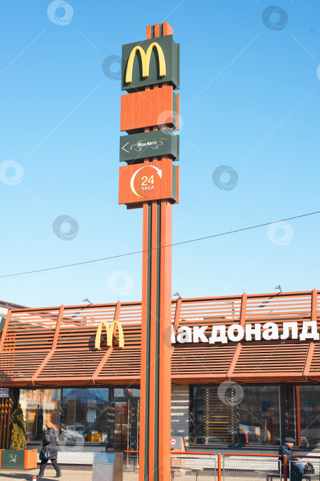 Скачать Семейный ресторан быстрого питания McDonald's, указатель на фоне ясного голубого неба. Вывеска, логотип на фасаде здания в солнечный день. Смоленск, Россия 04.12.2021 фотосток Ozero