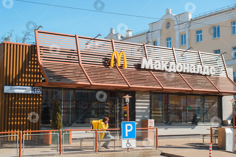 Скачать Семейный ресторан быстрого питания McDonald's на улице. Вывеска, логотип на фасаде здания в солнечный день. Смоленск, Россия 04.12.2021 фотосток Ozero